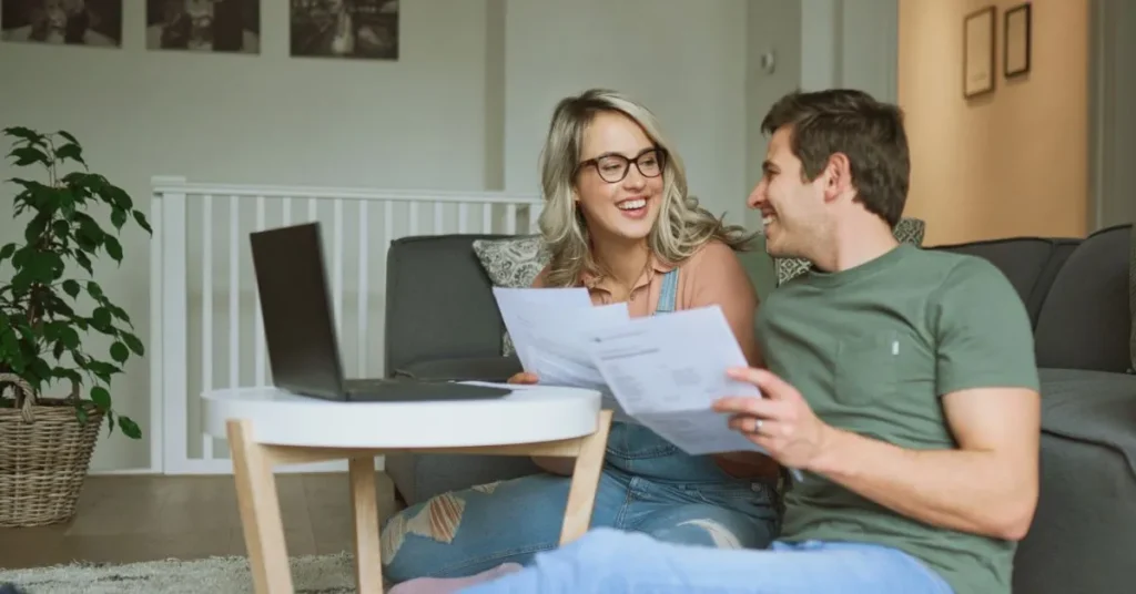 Casal sorrindo enquanto conversa sobre regime de bens do casamento com documentos em mãos.