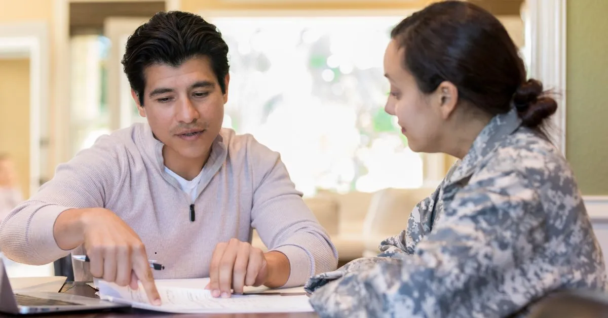 Casal revisando documentos de partilha de bens na união estável; mulher militar em uniforme e homem apontam cláusulas.