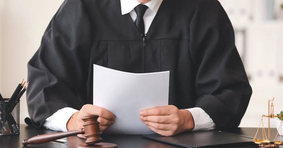 Documento jurídico ao lado de carimbo e miniatura de casa representando inventário judicial ou extrajudicial