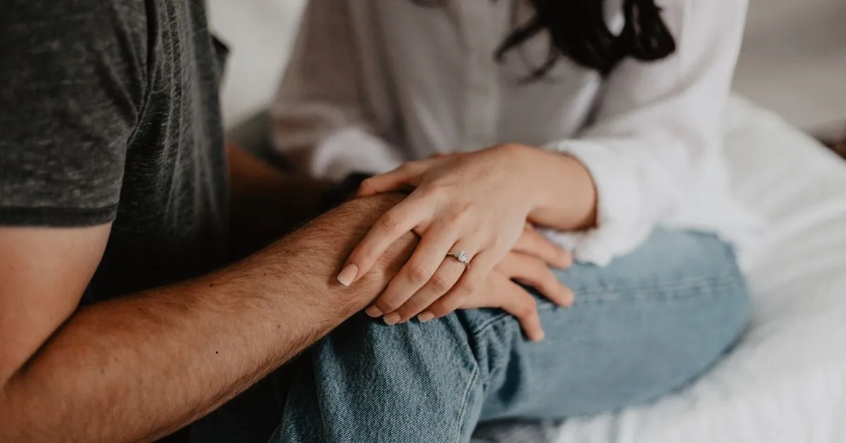 Casal sentado de mãos dadas, com anel de compromisso, simbolizando regime de bens na união estável