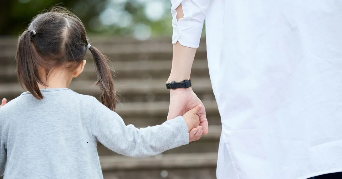 Mãe segurando a mão da filha após mudança de cidade para revisar a guarda dos filhos