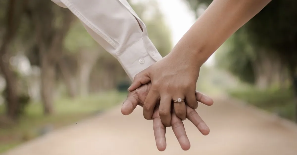 Mãos dadas simbolizando união estável com pessoa casada; aliança visível no anelar.