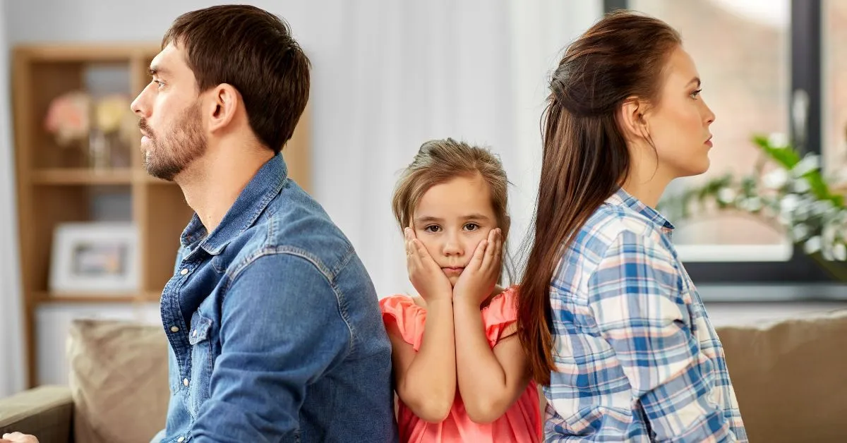 Criança triste entre pai e mãe de costas ilustra alienação parental durante o divórcio
