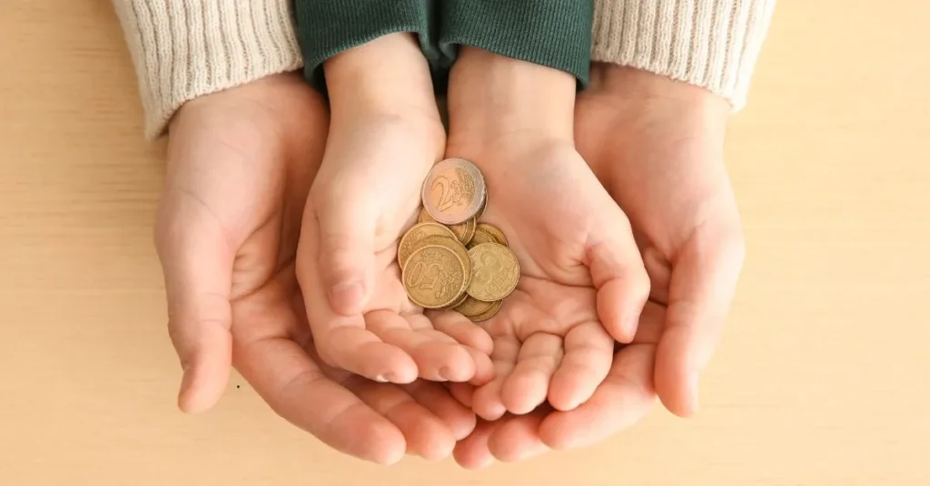Mãos de adulto e criança segurando moedas, representando redução de pensão alimentícia
