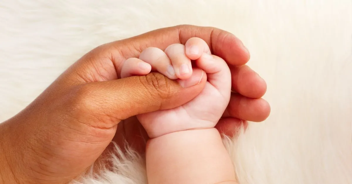 Mão de adulto segurando a mão de um bebê, simbolizando vínculo entre pais e filhos fora do casamento.