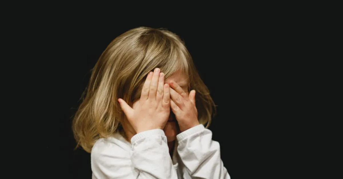 Guarda dos Filhos e Alienação Parental com criança cobrindo o rosto, simbolizando impacto emocional do conflito e possível intervenção da Justiça