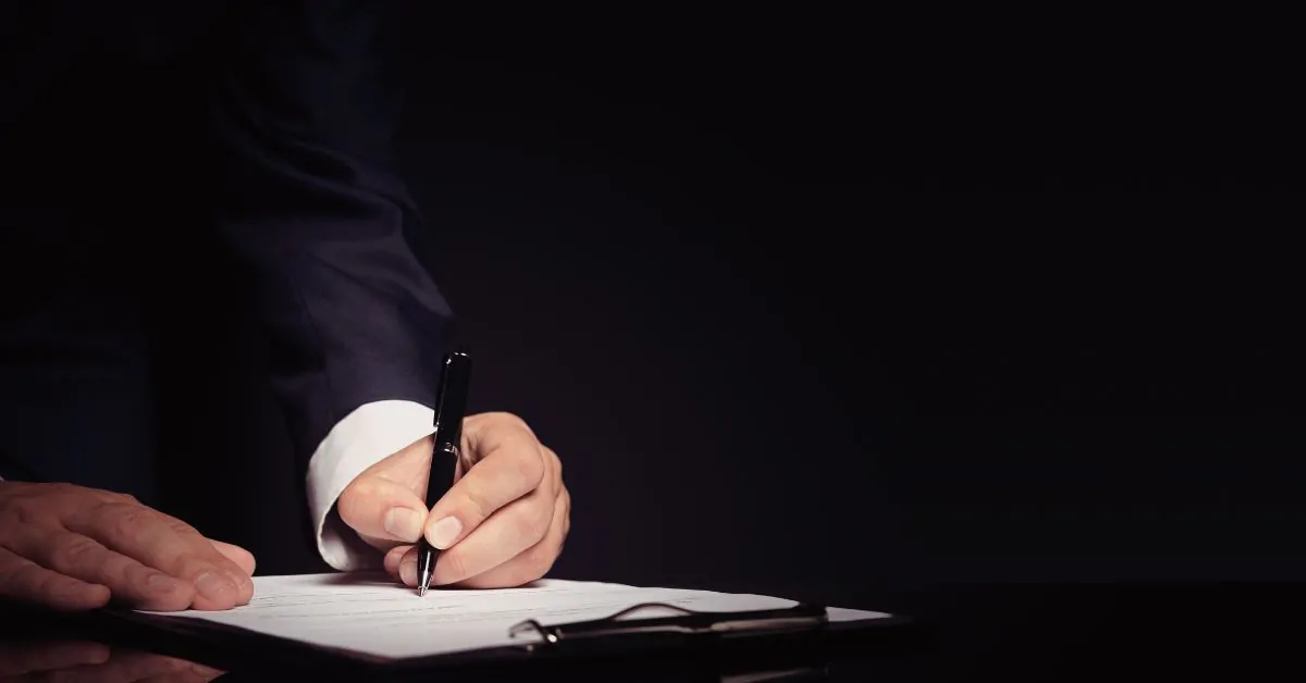 Pessoa assinando documento em cartório representando casamento no papel ou união estável e seus efeitos no regime de bens