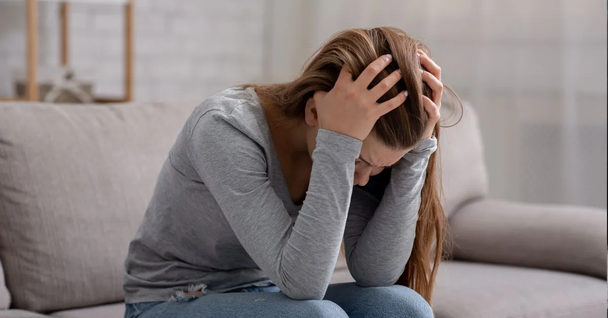 Pensão após o fim da união estável. Mulher preocupada no sofá com as mãos na cabeça, simbolizando dúvidas sobre direitos legais.