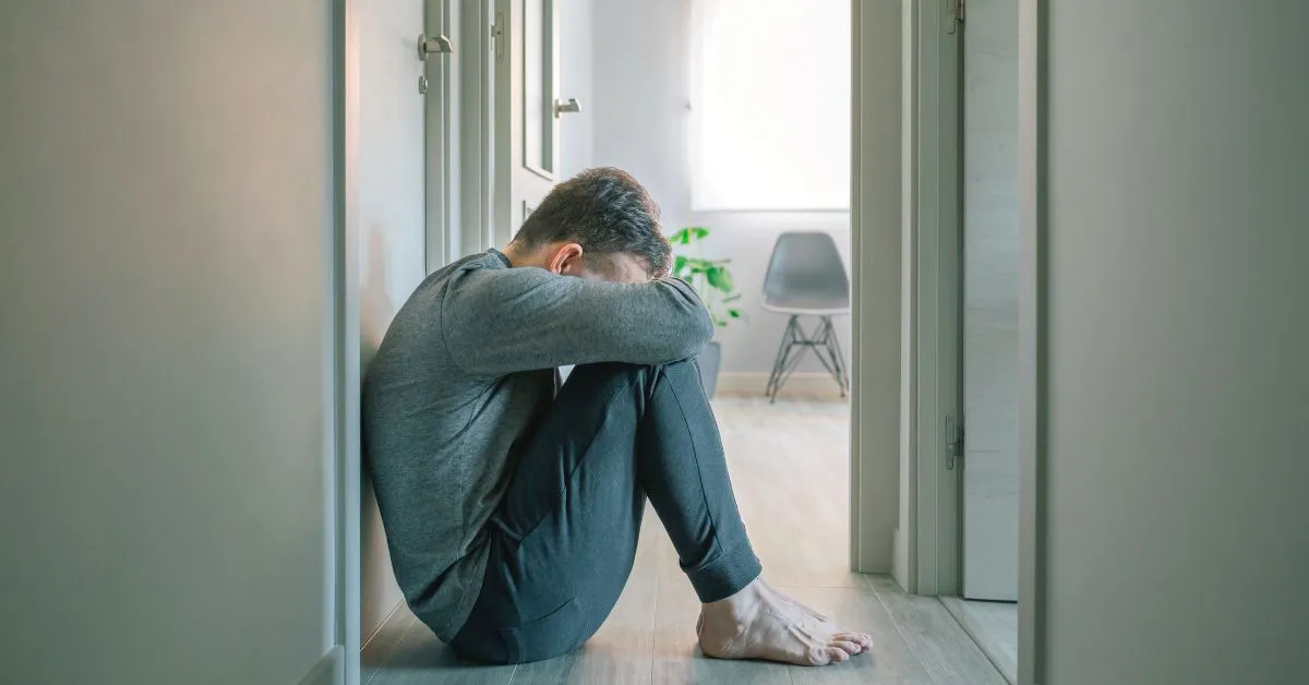 pai com transtorno mental sentado no corredor representando a dificuldade emocional em casos de guarda