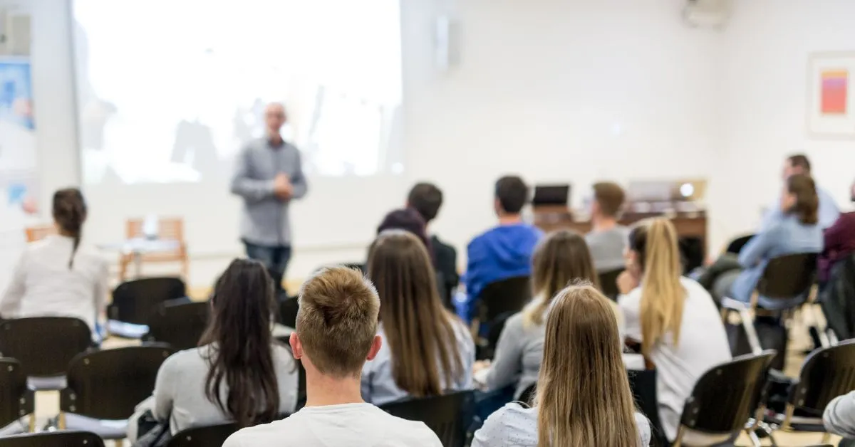 Estudantes universitários assistindo aula em sala de aula, ilustrando artigo sobre até quando é obrigatório pagar pensão para filho que faz faculdade.