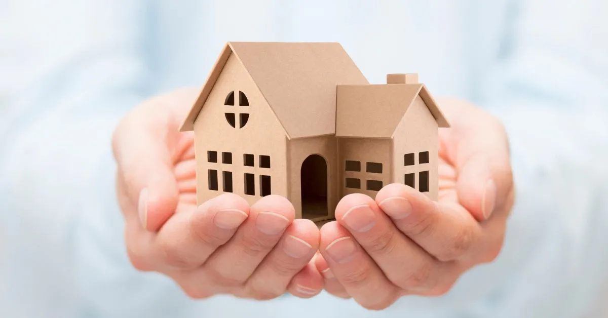 Mãos segurando uma miniatura de casa representando a venda de imóvel antes de finalizar o inventário.