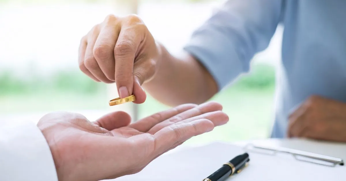 Pessoa devolvendo aliança após o divórcio, representando a decisão sobre o uso do nome de casado