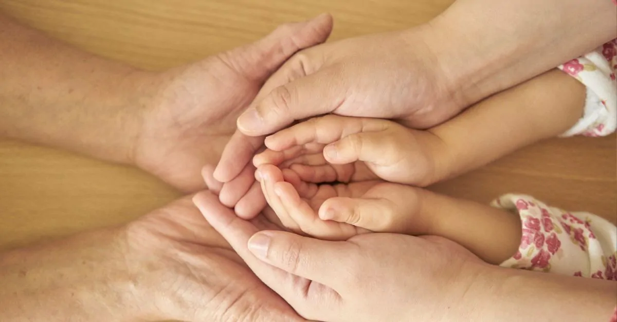 Mãos de gerações diferentes simbolizando proteção e continuidade familiar, representando o direito à herança e pensão por morte.