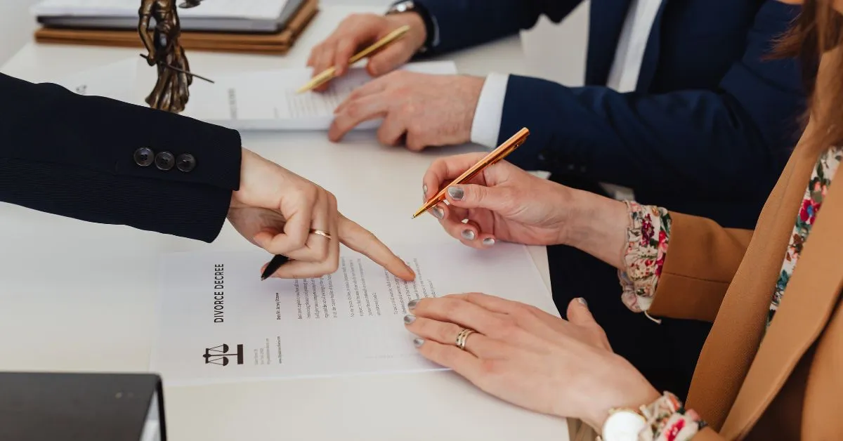 Casal assinando documentos de divórcio enquanto discute a partilha de bens anos depois da separação