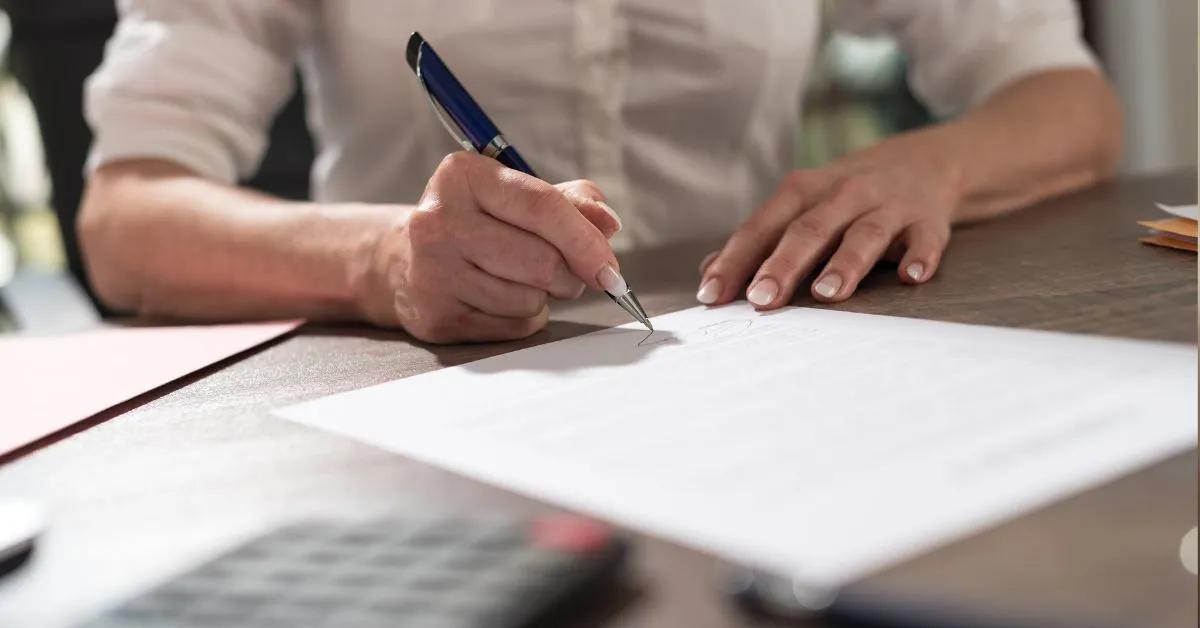Pessoa assinando documento para pacto antenupcial e entendimento da separação de bens convencional e obrigatória