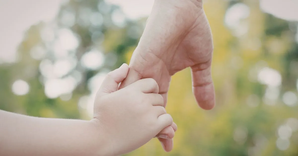 Mão de um adulto segurando a mão de uma criança, simbolizando responsabilidade na pensão paga por fora.