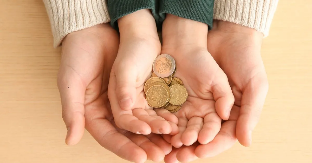 Criança segurando moedas nas mãos com apoio dos pais representando pensão alimentícia e despesas extraordinárias